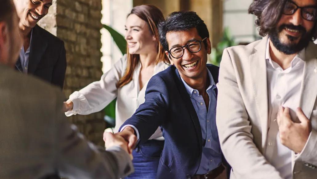 A group of laughing employees shake hands.