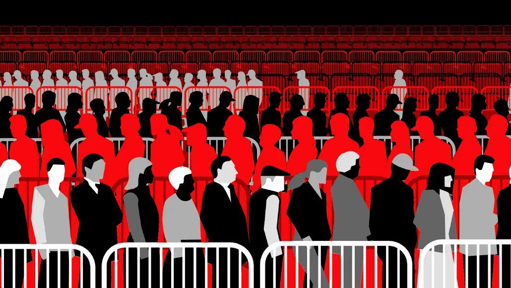 Metal portable barricades stretch back in rows as far as the eye can see. In the middle of the image, people form a queue within the barricades. The line snakes back and forth, making four rows all the way to the image foreground.