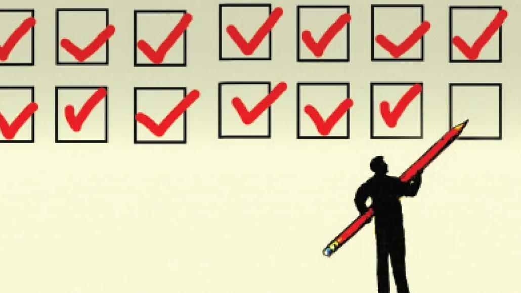 A person holds a giant pencil (longer than the person is tall) and stands in front of two rows of giant check boxes, each with a check in them as if they have been completed.