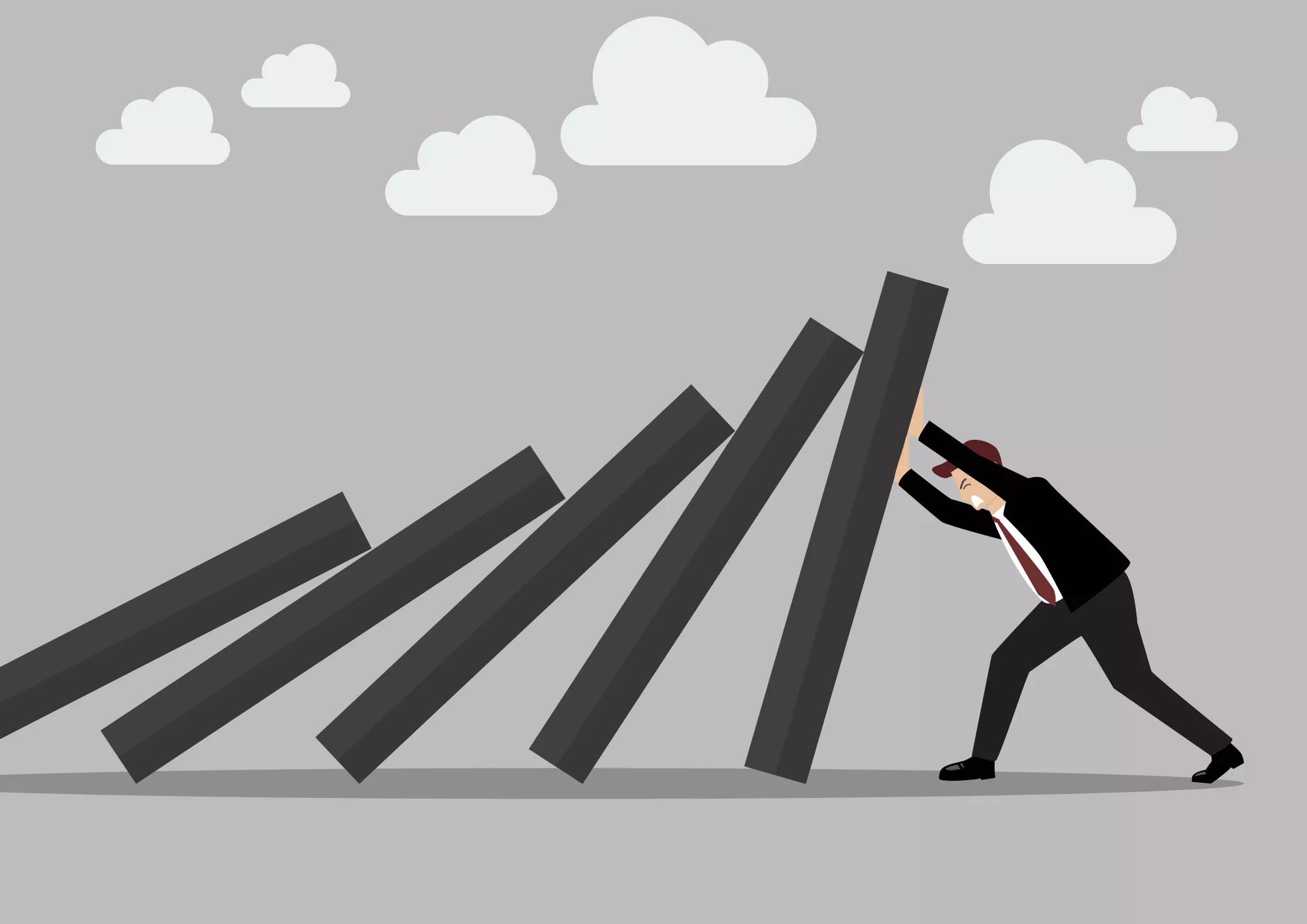 Businessman pushing hard against falling deck of domino tiles