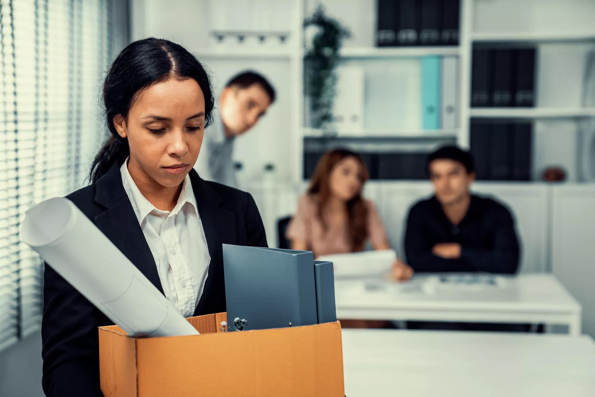 Depressed and disappointed employee packing her belongings after being fired for not being competent. Gossiped by her colleagues behind his back. Layoff due to economic depression.