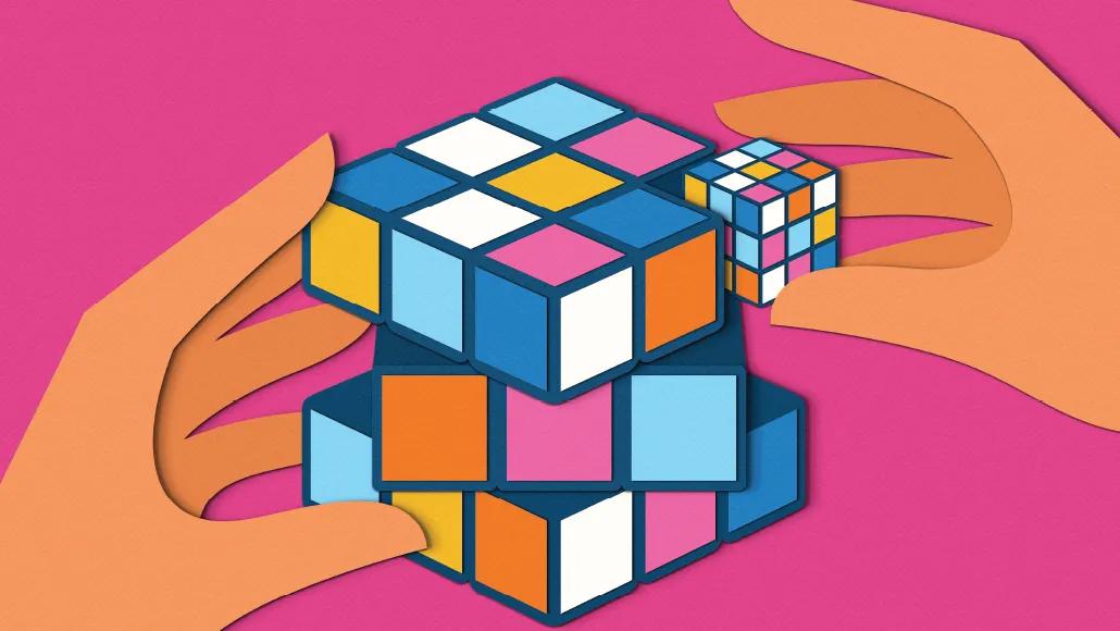 An illustration depicts a pair of hands holding one big rubix cube and one smaller rubix cube against a pink background