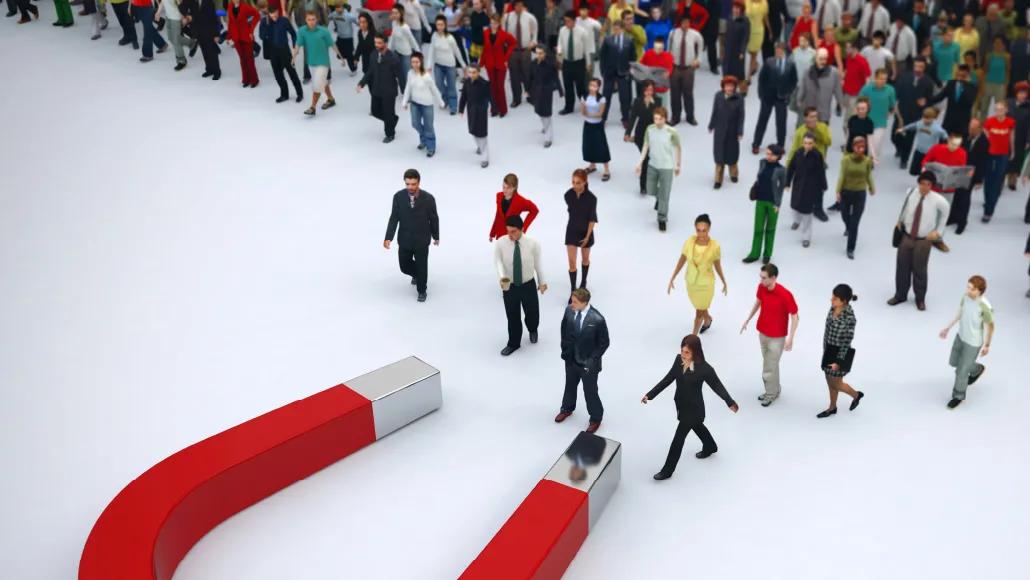 An illustration shows a horseshoe magnet attracting a group of miniature business-attired figures walking toward it.