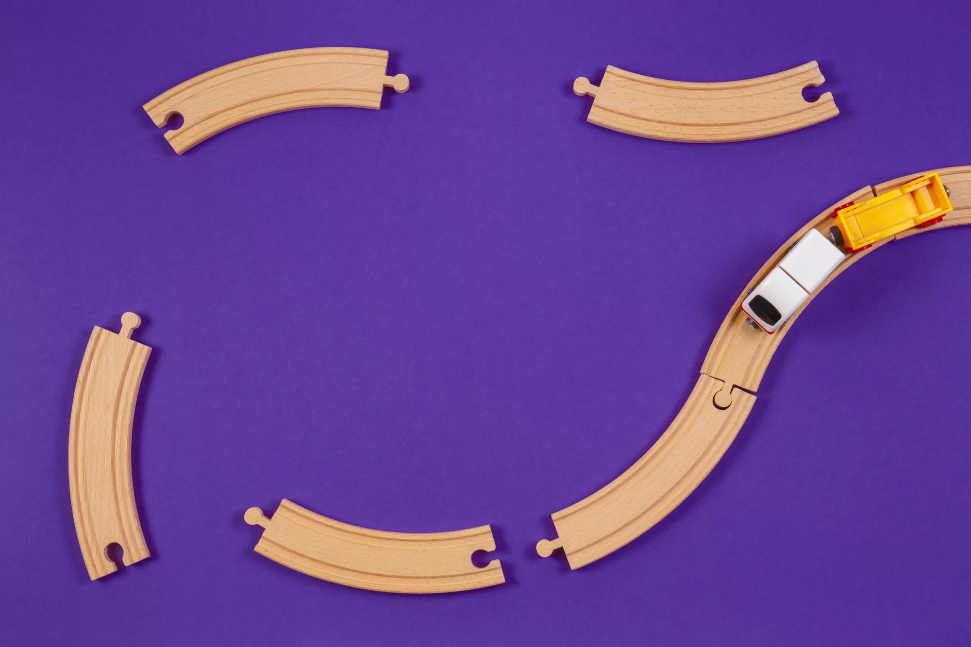 Toy train and wooden rails pieces on blue color background