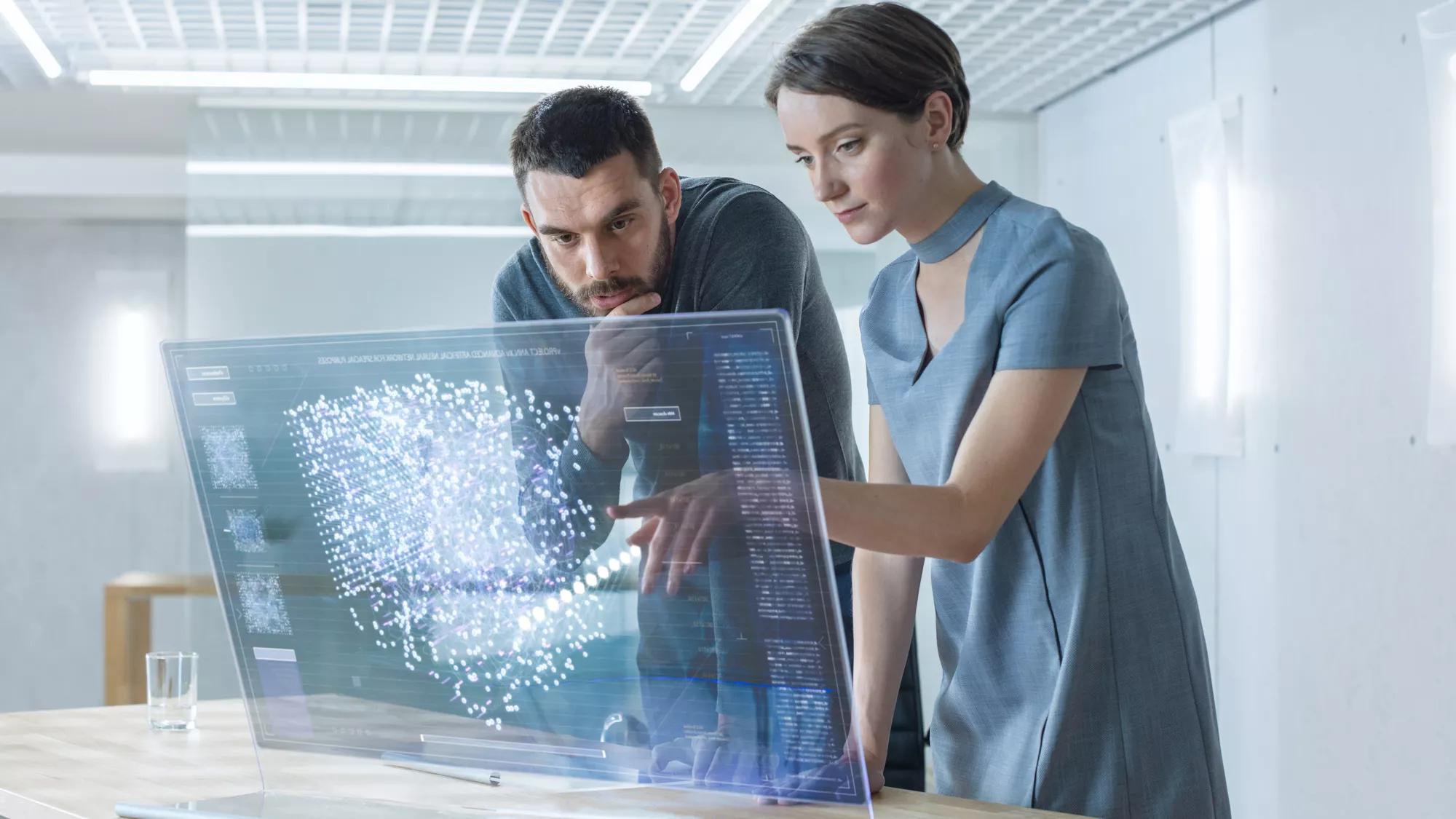 In the Near Future Male and Female Computer Engineers Talk While Working on the Transparent Display Computer. Screen Shows Interactive Neural Network, Futuristic User Interface.