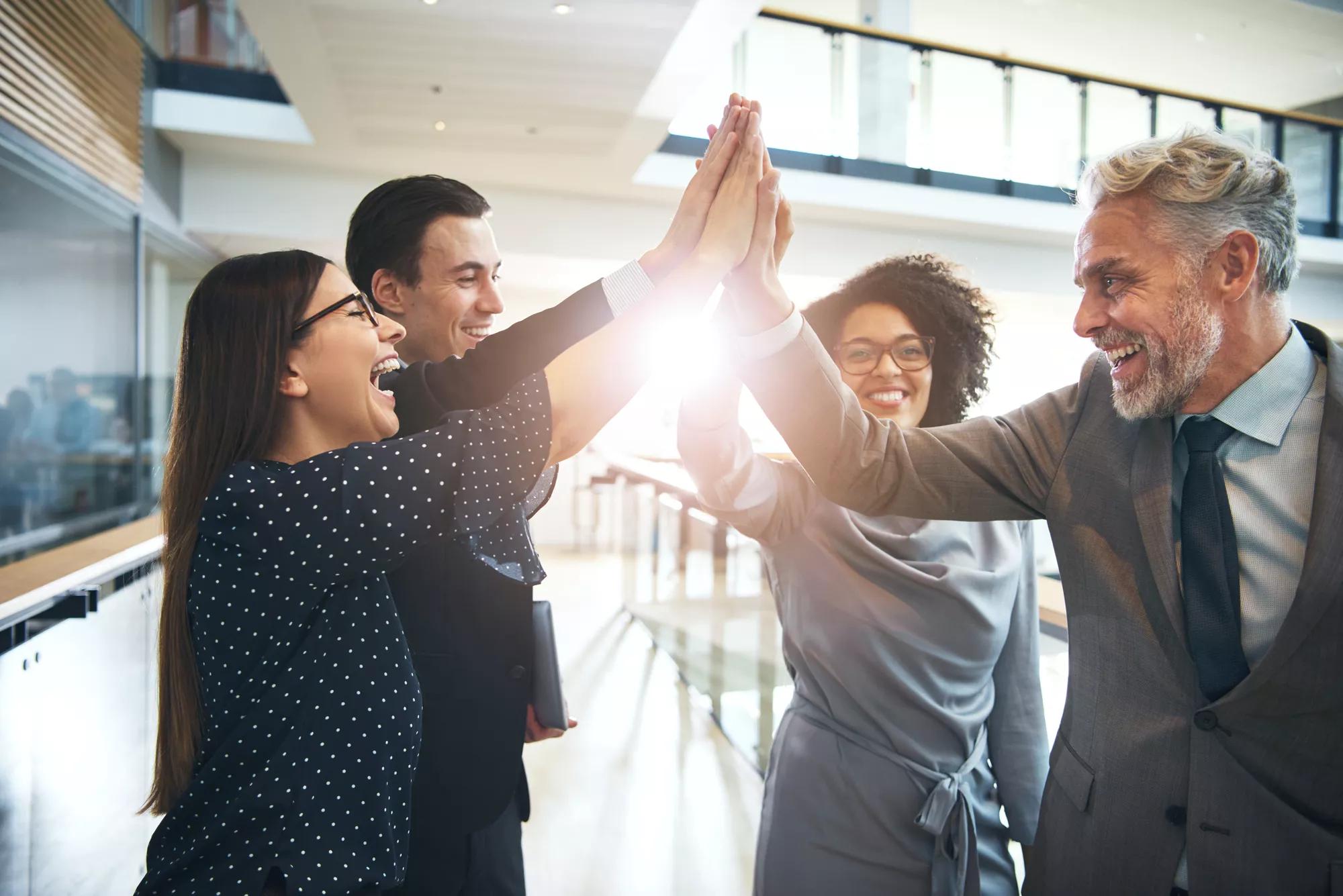 Laughing multiethnic team giving high five in office