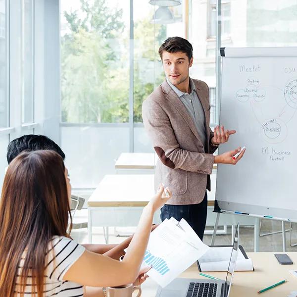 Confident businessman giving office presentation to coworkers using a flipchart.