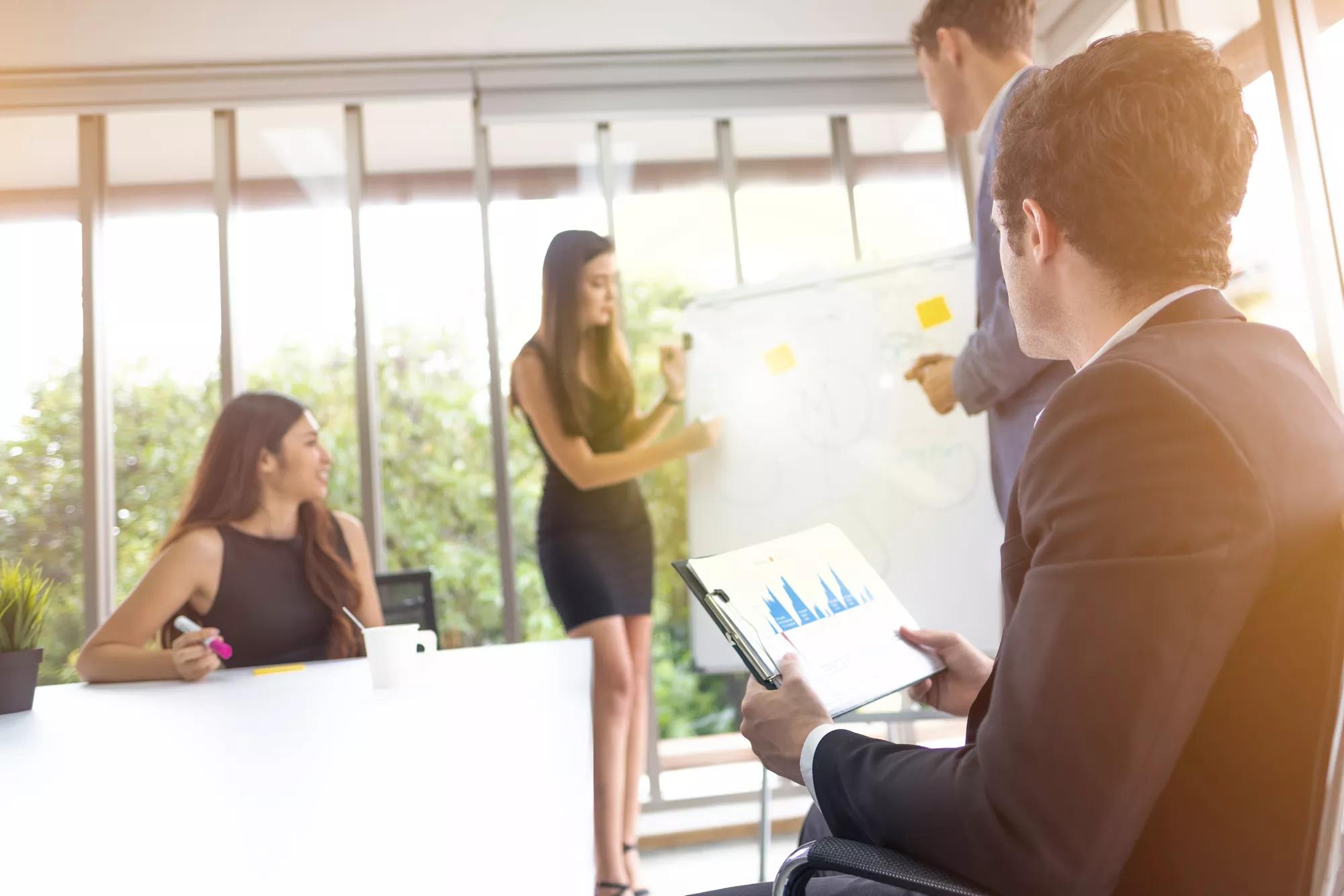 Group of people team listening to one of their colleagues present her results to team and boss give some advice after present.