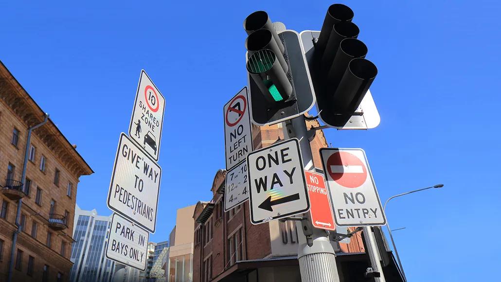 A photo of numerous street signs and traffic lights indicating a variety of messages