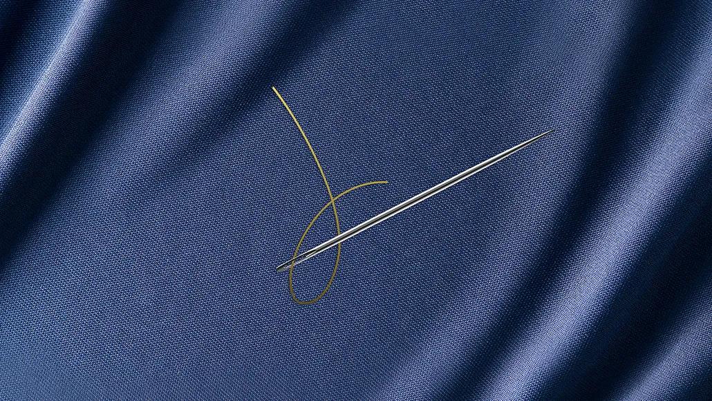 A needle and thread on a textured fabric like Oxford cloth.