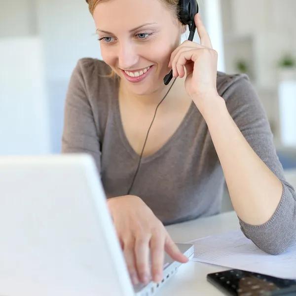 A facilitator uses a headset to while looking a her laptop screen.