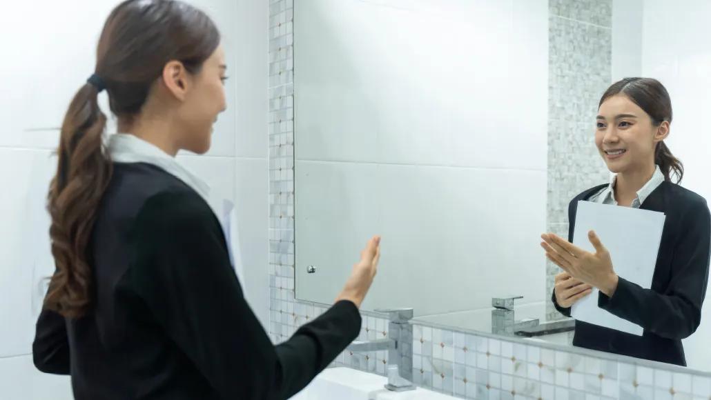 A photo shows a woman rehearsing in the mirror.