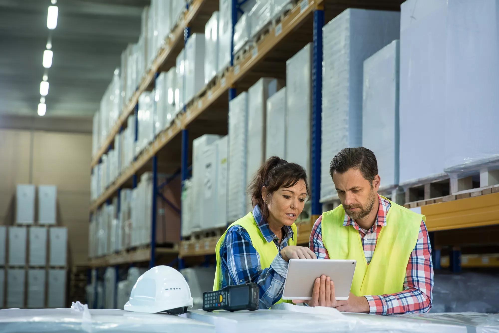 Man and a woman have short meeting in a warehouse and checking inventory levels of goods. First in first out, Last in last out, team working together concept photo.