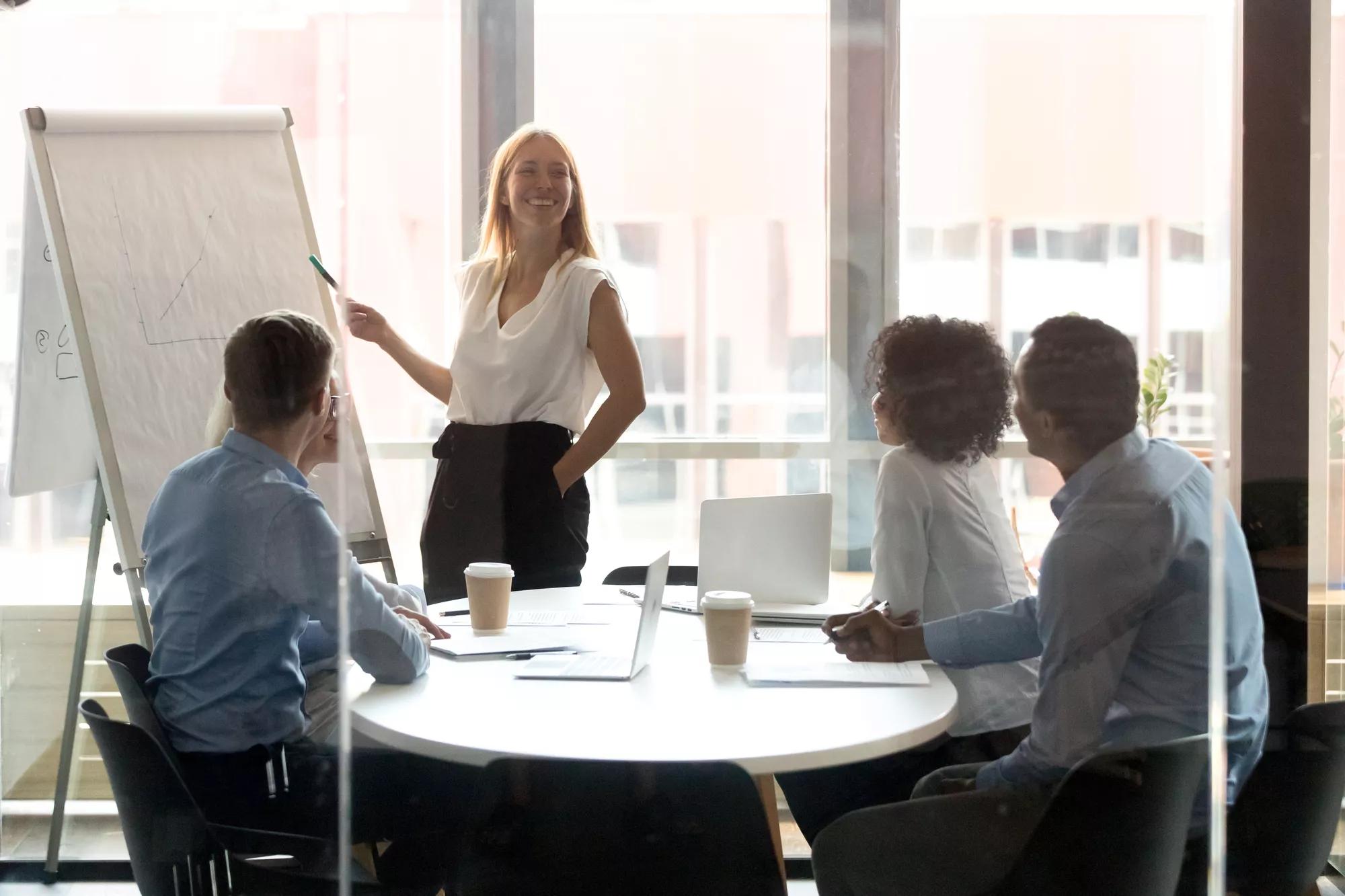 Happy female leader presenting work results at workshop in boardrooom